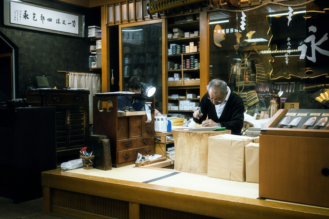 Japanese senior man practicing calligraphy with a brush in a workshop
