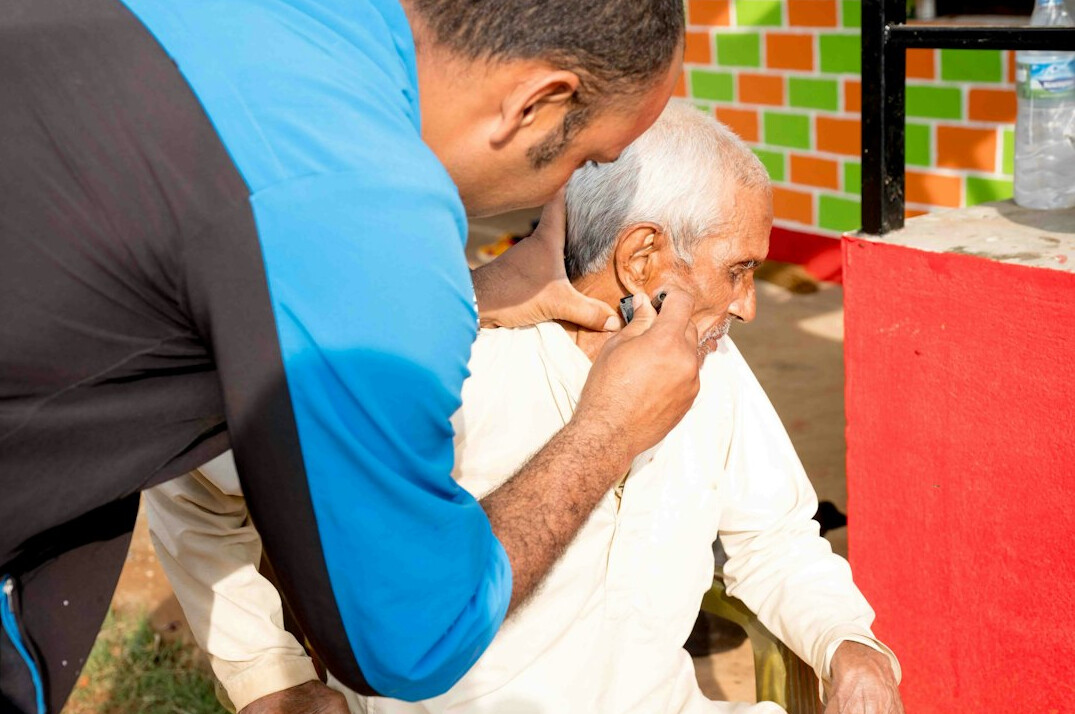 Staff member helping a Japanese senior at a community reception desk