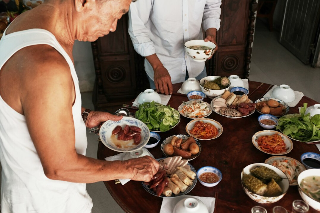 Japanese seniors enjoying a meal together at a long table in a community hall