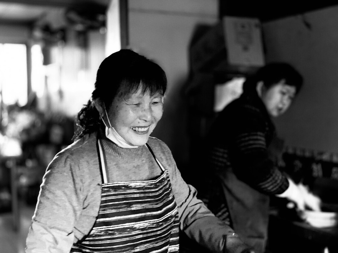 Japanese seniors smiling while chopping vegetables together in a home-style cooking class